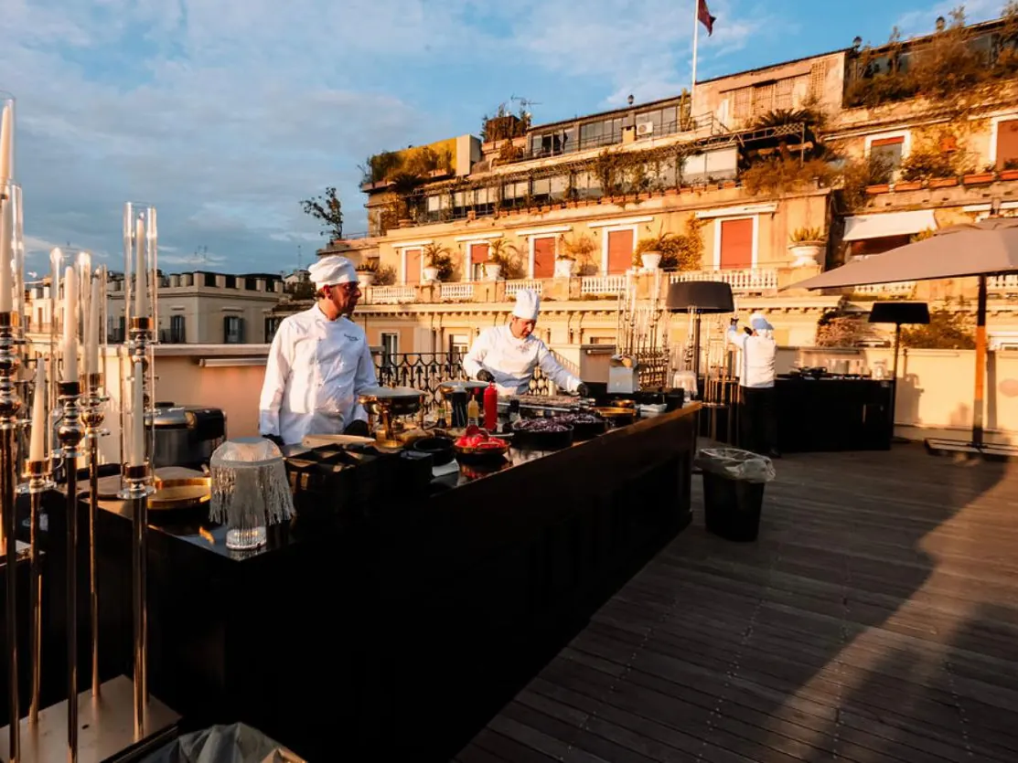 Cucina dal vivo su una terrazza panoramica al tramonto, con i tetti di Roma sullo sfondo