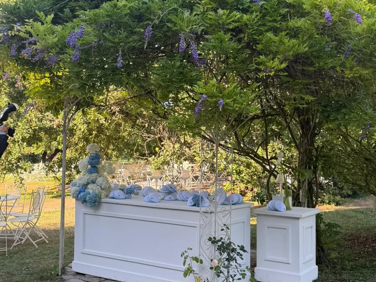 Banco buffet allestito sotto una pergola di glicine in fiore