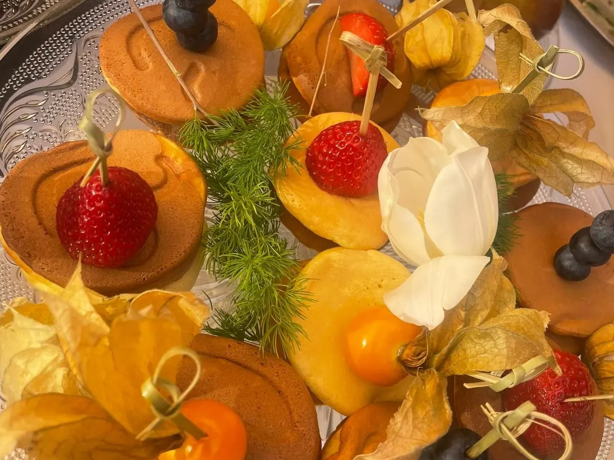 Finger food colorati con frutta fresca disposti su vassoio di legno